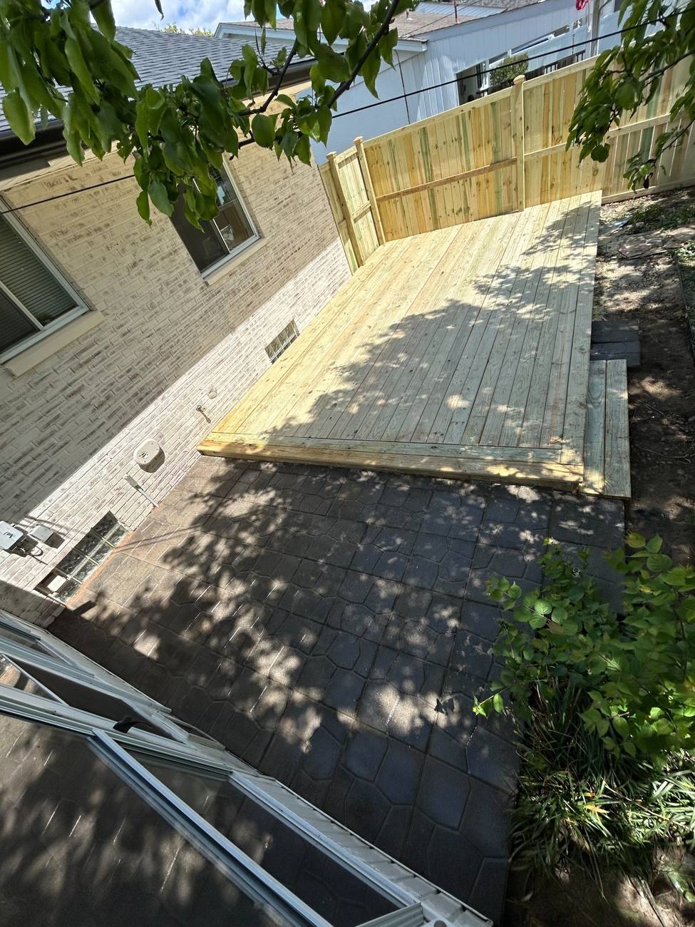 Deck with built-in privacy wall beside a brick home