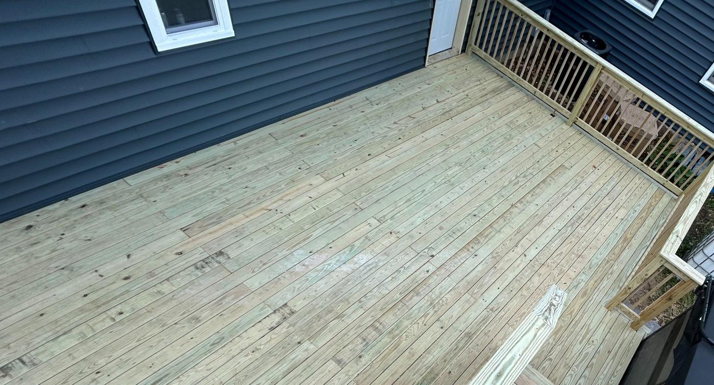 New deck with railings beside blue siding