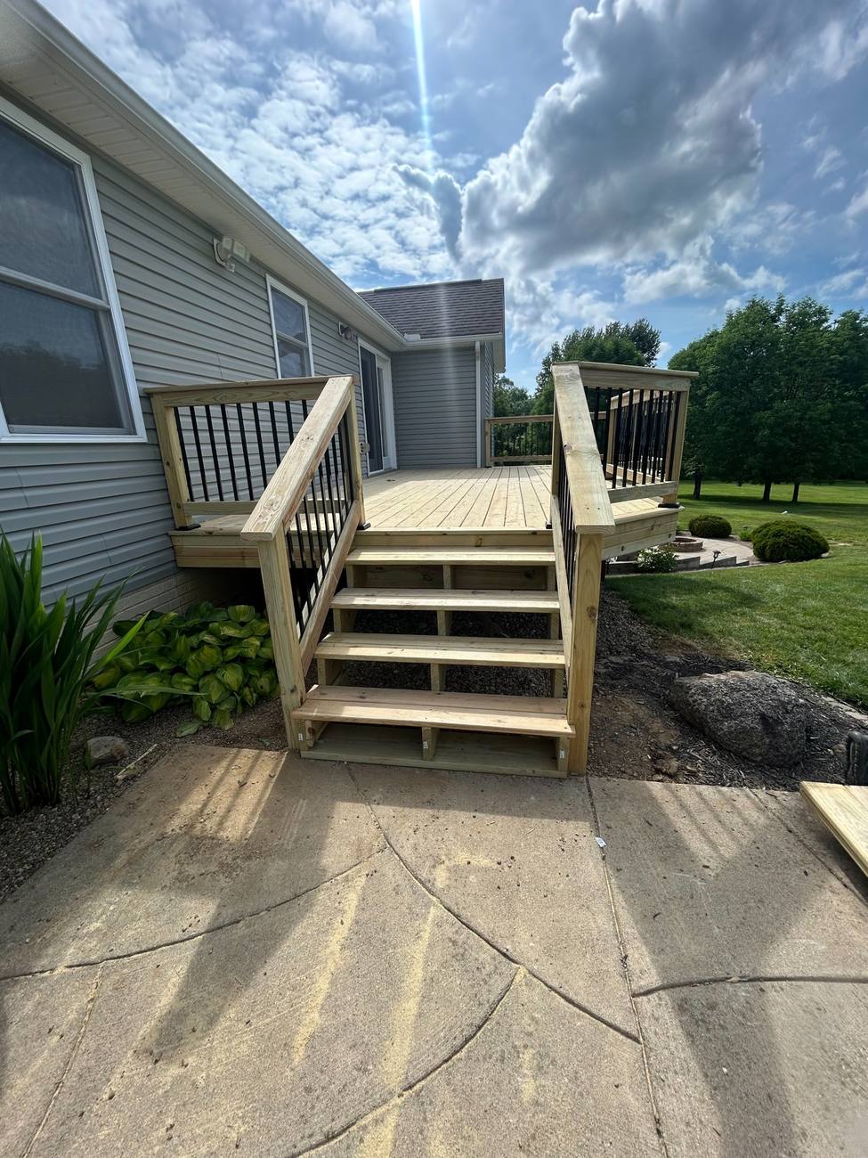 New deck with wide stairs and black baluster railings