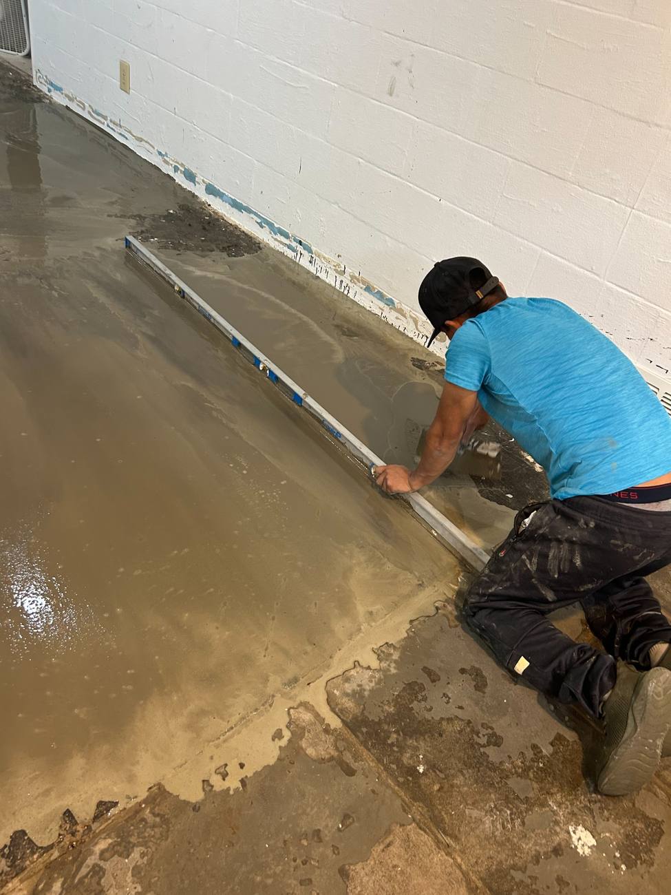 Crew member screeding a self-leveling basement floor