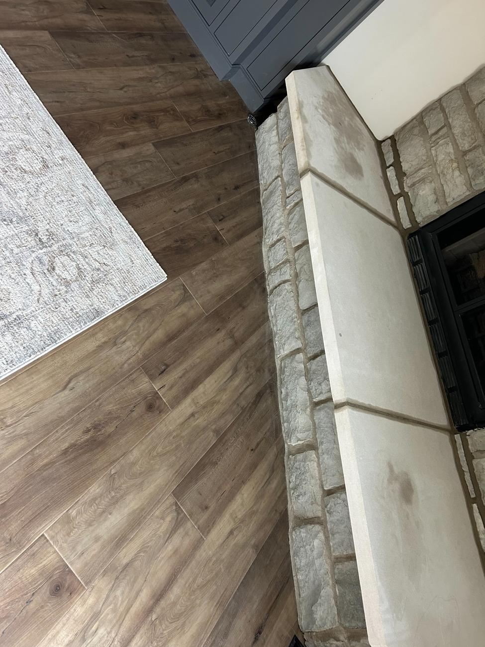 Wood-look plank flooring meeting a stone fireplace hearth