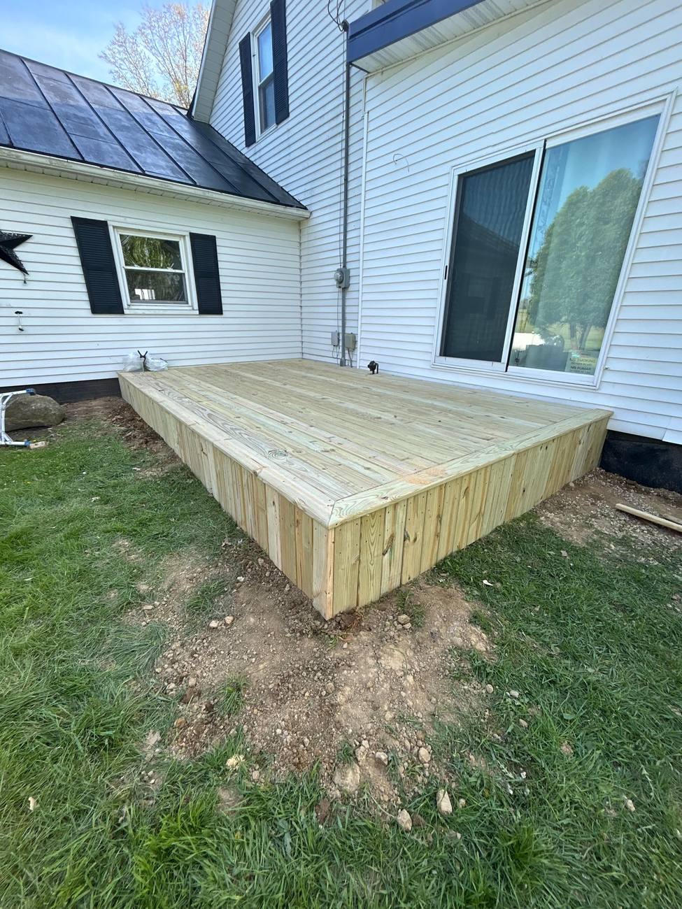 Skirted deck off the back of a white farmhouse