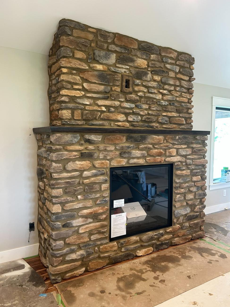 Stacked stone fireplace with wood mantel